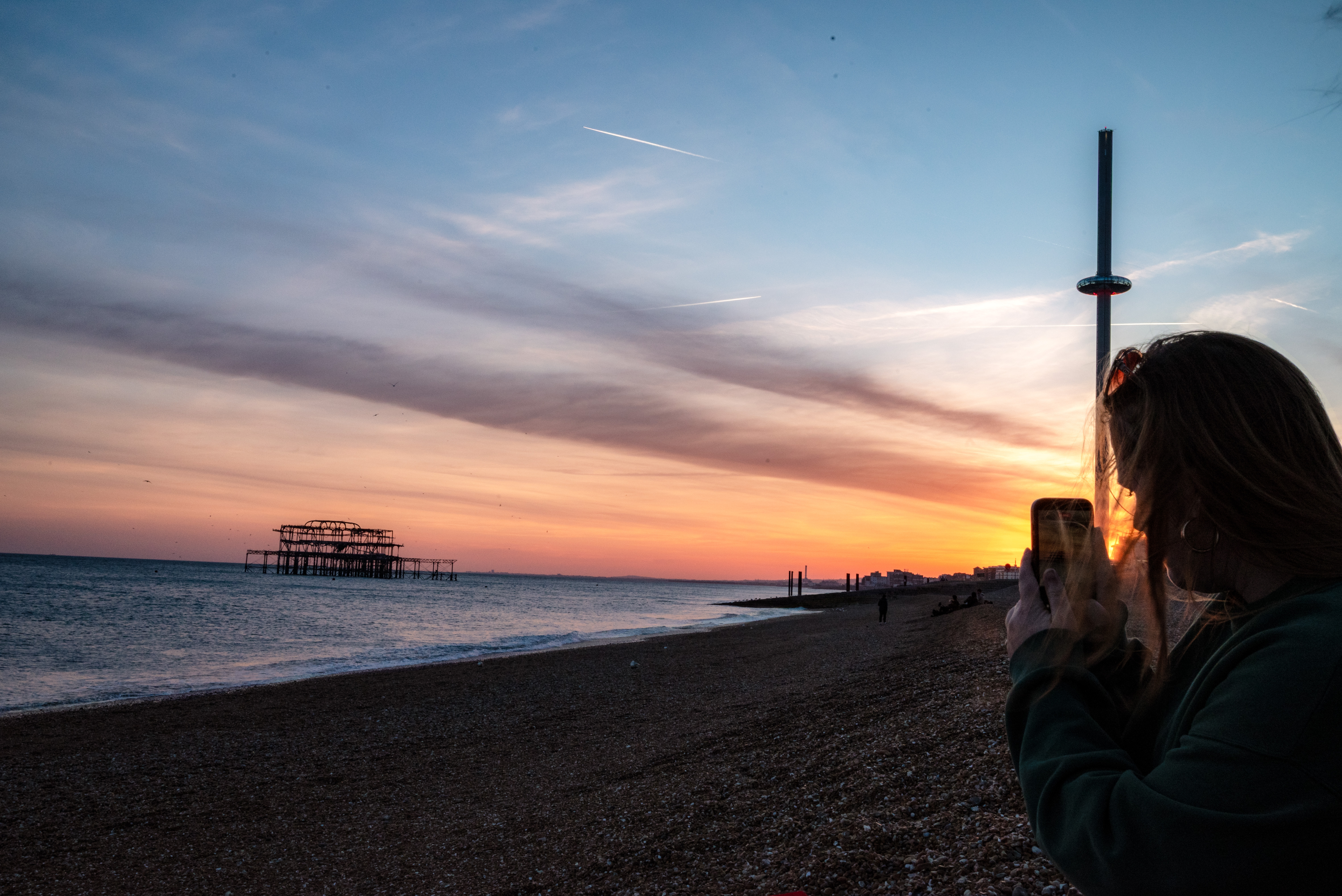 sunset: a girl taking a picture of the sunset